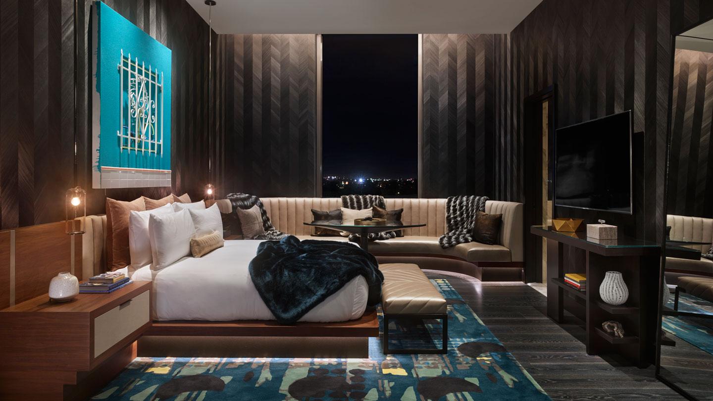 The mezzanine guest bedroom has a dark, muted palette with a chevron wood wall covering.