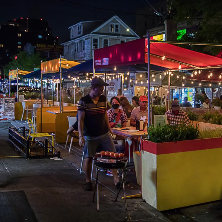People dining outdoors in dining booth on the street at night