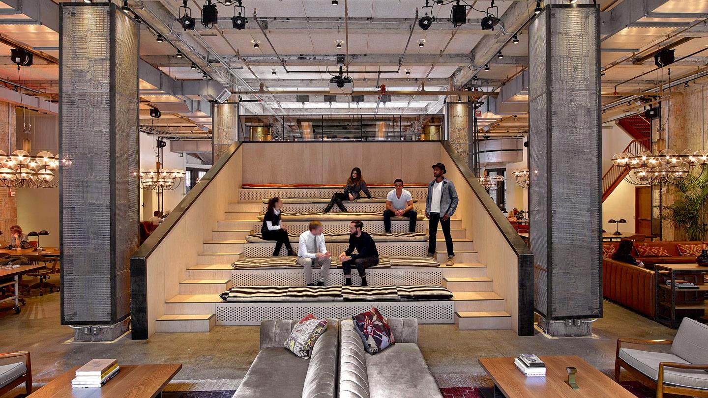 People sitting on steps at NeueHouse New York designed by Rockwell Group architects
