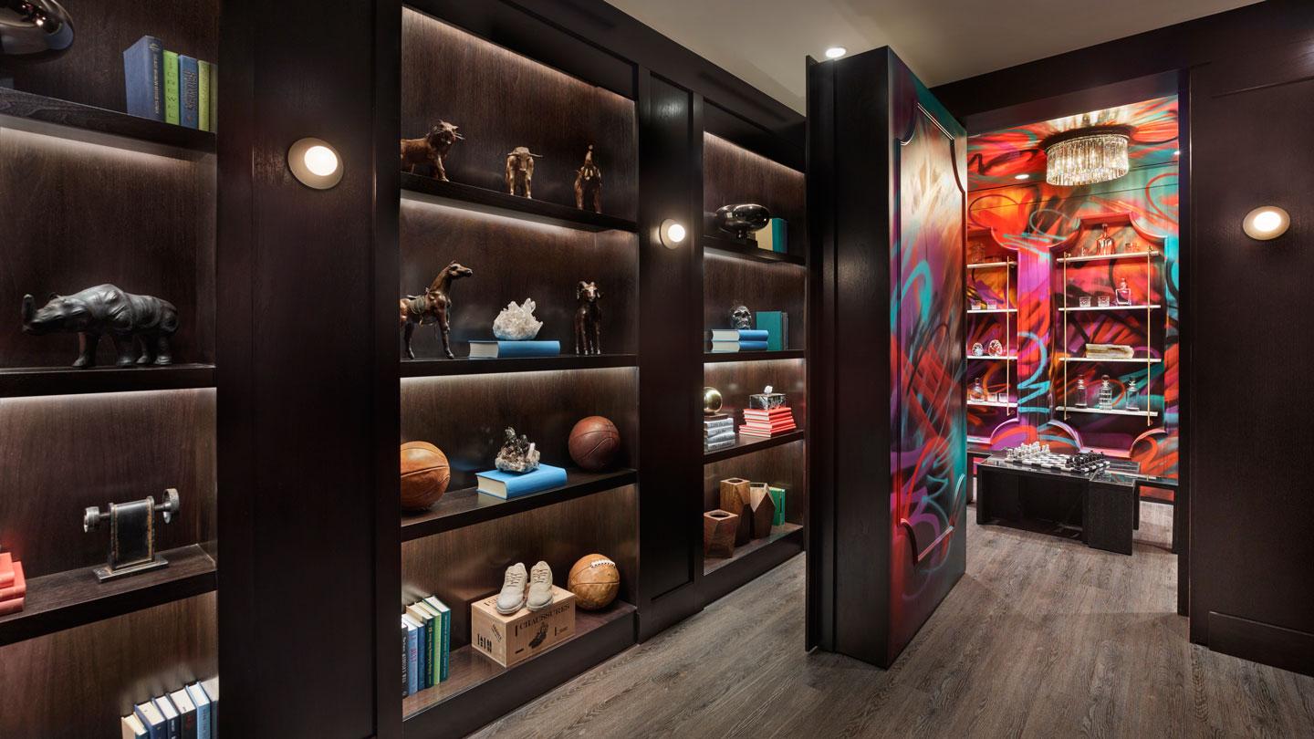 A library bookcase wall doubles as a secret door that rotates to reveal a private whiskey room.