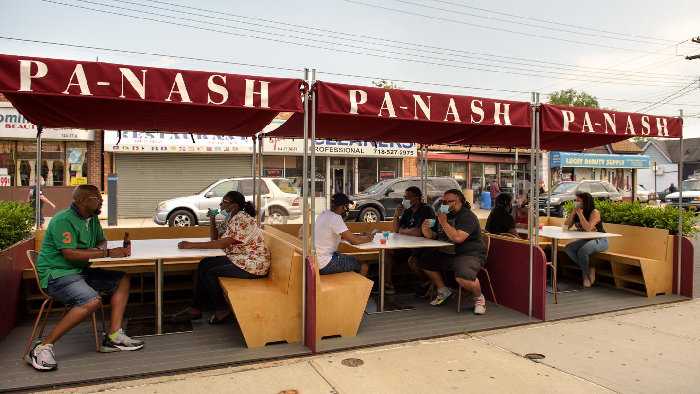 People dining inside 3 outdoor DineOut dining pavilions on street outside of restaurant in Queens